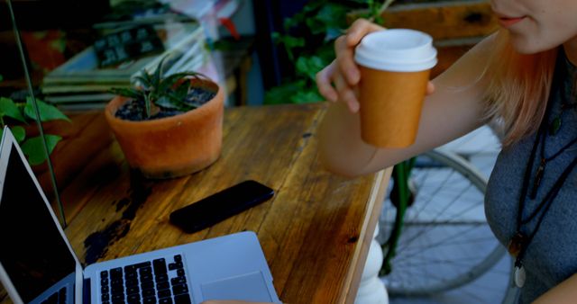 Young Woman Drinking Coffee and Browsing Laptop at Outdoor Cafe - Download Free Stock Images Pikwizard.com