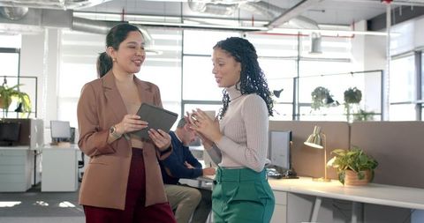 Diverse Female Colleagues Collaborating with Tablet in Bright Open-Plan Office