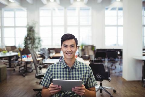 Young Man Using Tablet in Modern Open-Plan Office Setting