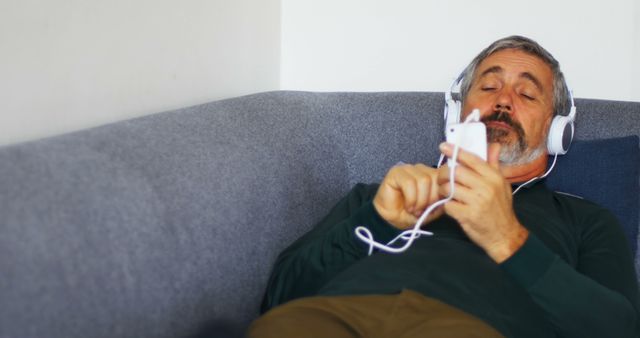 Mature Man Relaxing on Couch with Headphones and Smartphone - Download Free Stock Images Pikwizard.com