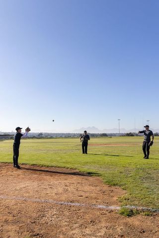 Three Men Practicing Baseball Catching on Sunny Field Throwing Ball During Team Drill