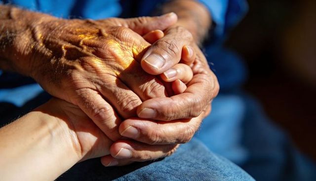 Elderly hands clasping younger hand closeup conveying warmth care and lasting support