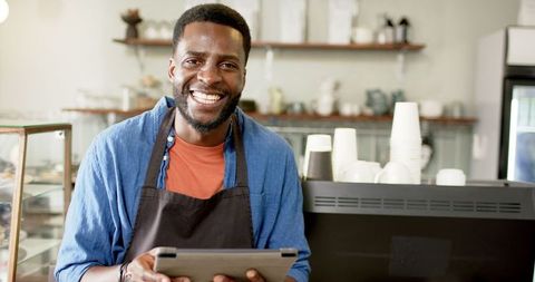 Friendly Barista Smiling Holding Tablet in Cozy Café Environment