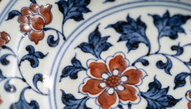 Handpainted porcelain plate featuring orange floral medallion and blue vine pattern