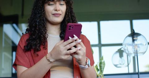 African american woman using smartphone and smartwatch in modern coworking lounge