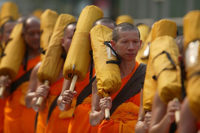 Buddhist monks marching together with bundles over their shoulders signifies unity and purpose in an important ritual. Ideal for illustrating articles on Buddhism, spirituality, meditation, cultural practices, religious ceremonies, or educational resources about Buddhist traditions.