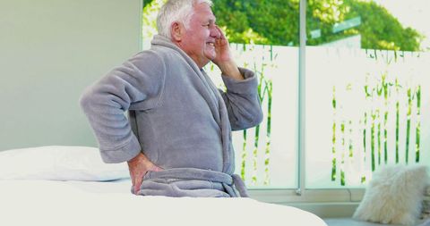 Senior Man Experiencing Back and Head Pain at Home