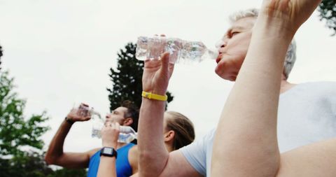 Diverse group hydrating after exercise with outdoor background
