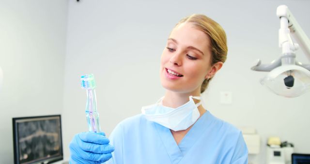 Young dentist examining a dental brush in modern clinic. Ideal for promoting dental services, educational materials for dental hygiene, or healthcare profession content. Bright and professional atmosphere highlights the importance of dental care and skilled practitioners.