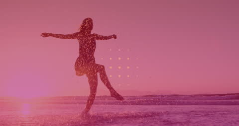 Joyful Woman Frolicking in Ocean at Sunset with Sparkling Lights