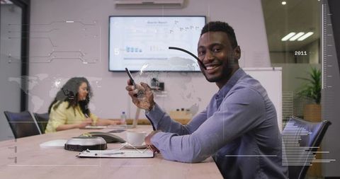 Smiling businessman holding phone at meeting table showcasing collaboration and technology