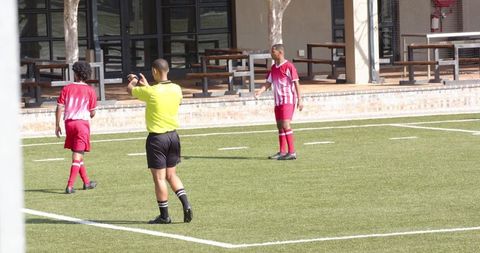 Referee and Players on Soccer Field During Competitive Match