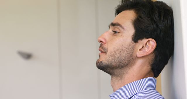 Stressed Young Man Leaning Against Wall in Office - Download Free Stock Images Pikwizard.com