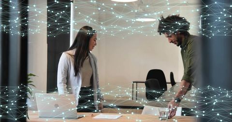 Collaborating professionals reviewing documents in modern office with network overlay