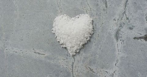 Heart-shaped pile of salt on stone kitchen worktop