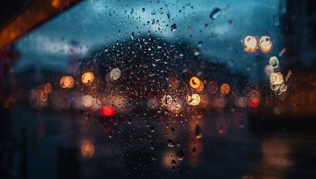 Moody Reflections on Rain-Kissed City Windowpane at Dusk