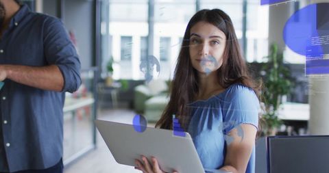 Businesswoman Holding Laptop in Modern Office with Digital Charts