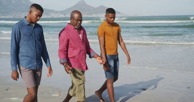 Father and sons walking along the beach, engaged in pleasant conversation, enjoying quality time together. Ideal for portraying family bonds, outdoor activities, summer vacations, and concepts of happiness and togetherness.
