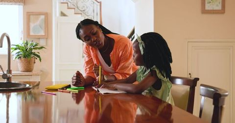 Mother and Daughter Doing Homework Together at Dining Table