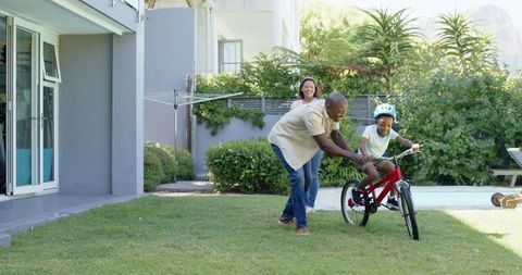 Father teaching son to ride bicycle in backyard, connection and joy