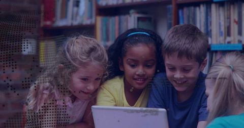 Elementary students collaborating around white laptop in school library for group learning