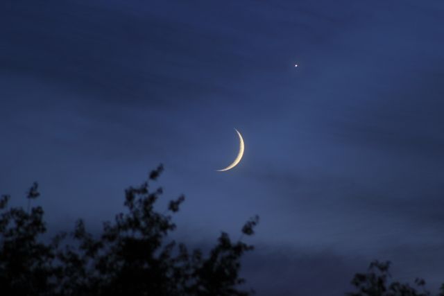 Crescent moon shining with a single star in a twilight sky, presenting a serene and peaceful evening scene. Perfect for use in astronomy articles, night-themed projects, or nature photography collections highlighting celestial beauty.