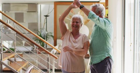 Smiling Senior Couple Enjoying Dance in Modern Home