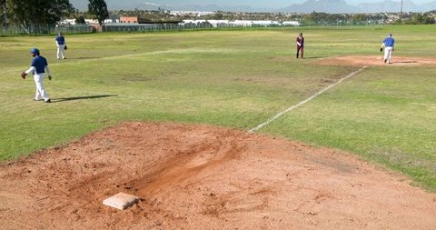 Baseball Players Practicing on Grassy Field Under Clear Sky