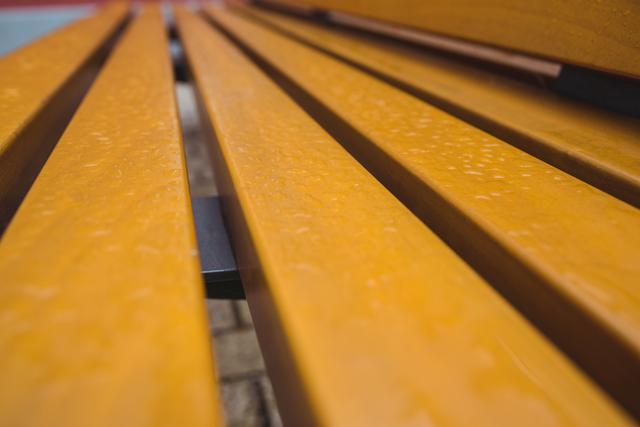 Close-up view of wooden strips on a bench with visible water droplets. Ideal for use in backgrounds, textures, and materials. Suitable for illustrating outdoor seating, natural materials, and rainy weather themes.