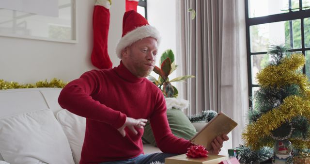 Man Celebrating Christmas Unwrapping Gift in Festive Living Room - Download Free Stock Images Pikwizard.com