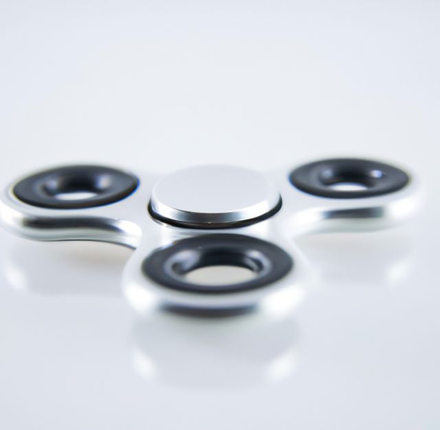 Image of close up of metallic fidget spinner on white background. Playing object and toy concept.