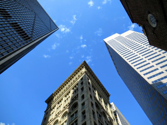 Tall skyscrapers and high-rise buildings dominate urban cityscape, standing against clear blue sky. Ideal for portraying modern architecture, business districts, and urban life, useful in projects requiring visuals for commercial real estate, corporate offices, or city planning.