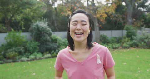 Joyful Woman Wearing Breast Cancer Awareness Ribbon Laughing Outdoors
