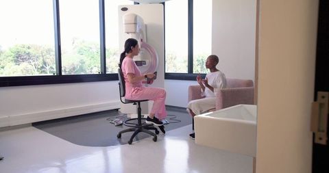 Mammography technologist consulting black patient during breast imaging appointment