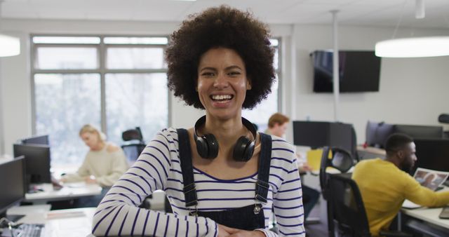 Young woman smiling in a casual office setting, creating a welcoming, inclusive workplace. Ideal for content on modern work culture, team collaboration, and positive work environments.