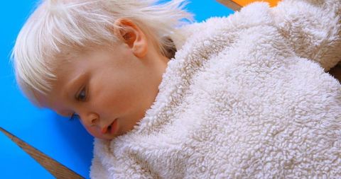 Cute Child Lying on Colorful Paper Engaging in Creative Activity