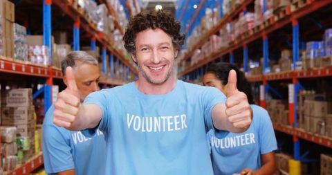 Happy Volunteer Giving Thumbs Up in Charity Warehouse