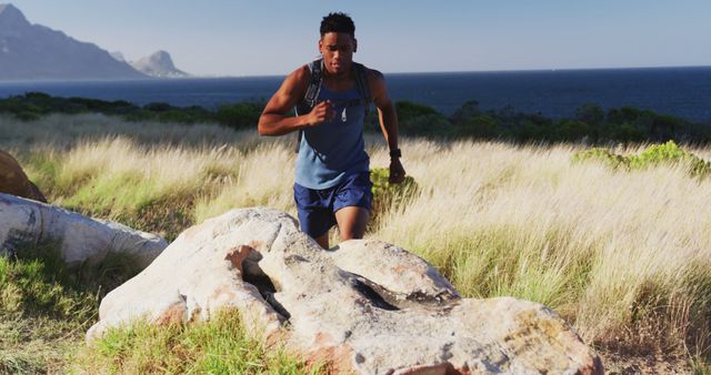 African american man exercising outdoors jumping on a rock in countryside on a mountain. Fitness training and healthy outdoor lifestyle.