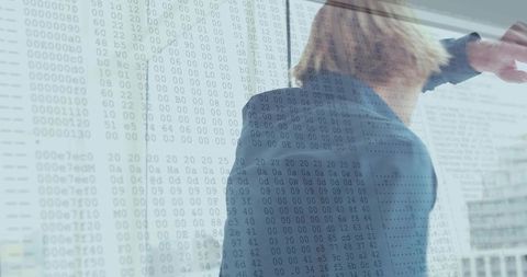 Businessman pointing through glass with data code overlay urban corporate analytics concept