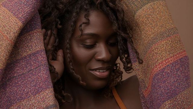 Smiling woman wearing colorful woven shawl with orange strap closeup portrait