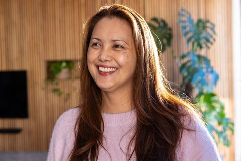 Smiling Asian Woman in Cozy Lounge Setting with Natural Decor