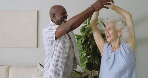 Senior Couple Dancing Joyfully in Living Room with Greenery