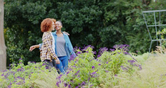 Happy diverse couple embracing and walking among plants in garden, copy space. Romance, relationship and healthy lifestyle, unaltered.