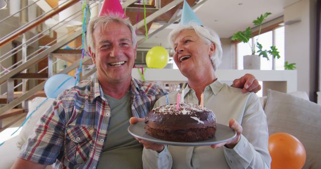 Portrait of senior caucasian couple holding cake celebrating birthday waving looking at camera at home. social distancing quarantine lockdown during coronavirus pandemic
