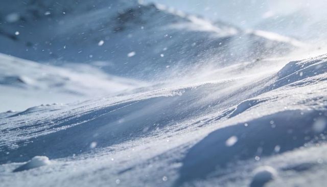 Wind-sculpted alpine snowdrift blowing ice crystals across sunlit blue mountain slope
