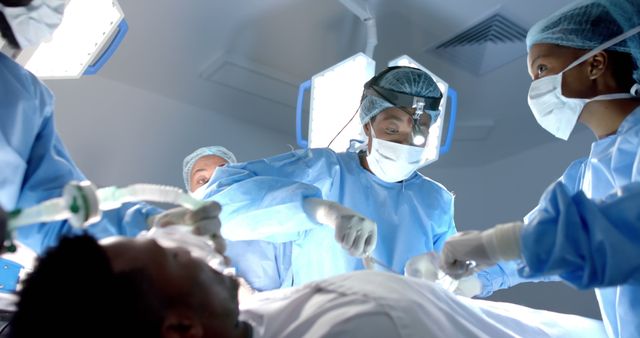 Team of surgeons performing a surgical procedure in a modern operating room. Medical professionals working in a sterile environment, providing patient care. Ideal for use in healthcare presentations, medical publications, and educational materials highlighting teamwork and advancements in modern surgery.