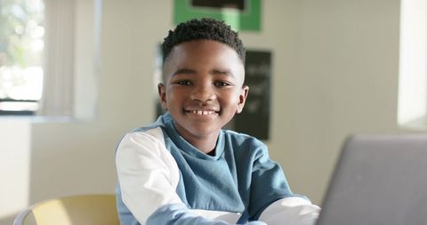 Smiling African Boy Studying on Laptop at Bright Home Desk