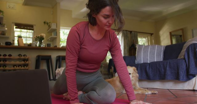 Woman enjoying a yoga session in her living room, accompanied by her pet dog. Great for promoting healthy living, at-home exercises, mental wellness, fitness routines, and the calming presence of pets.
