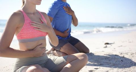 Couple Practicing Mindful Yoga Meditation on Beach Shoreline