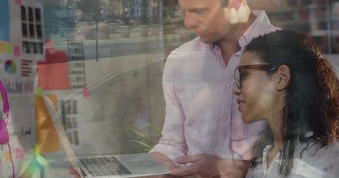 Lean team collaborating over laptop and sticky notes with city reflections